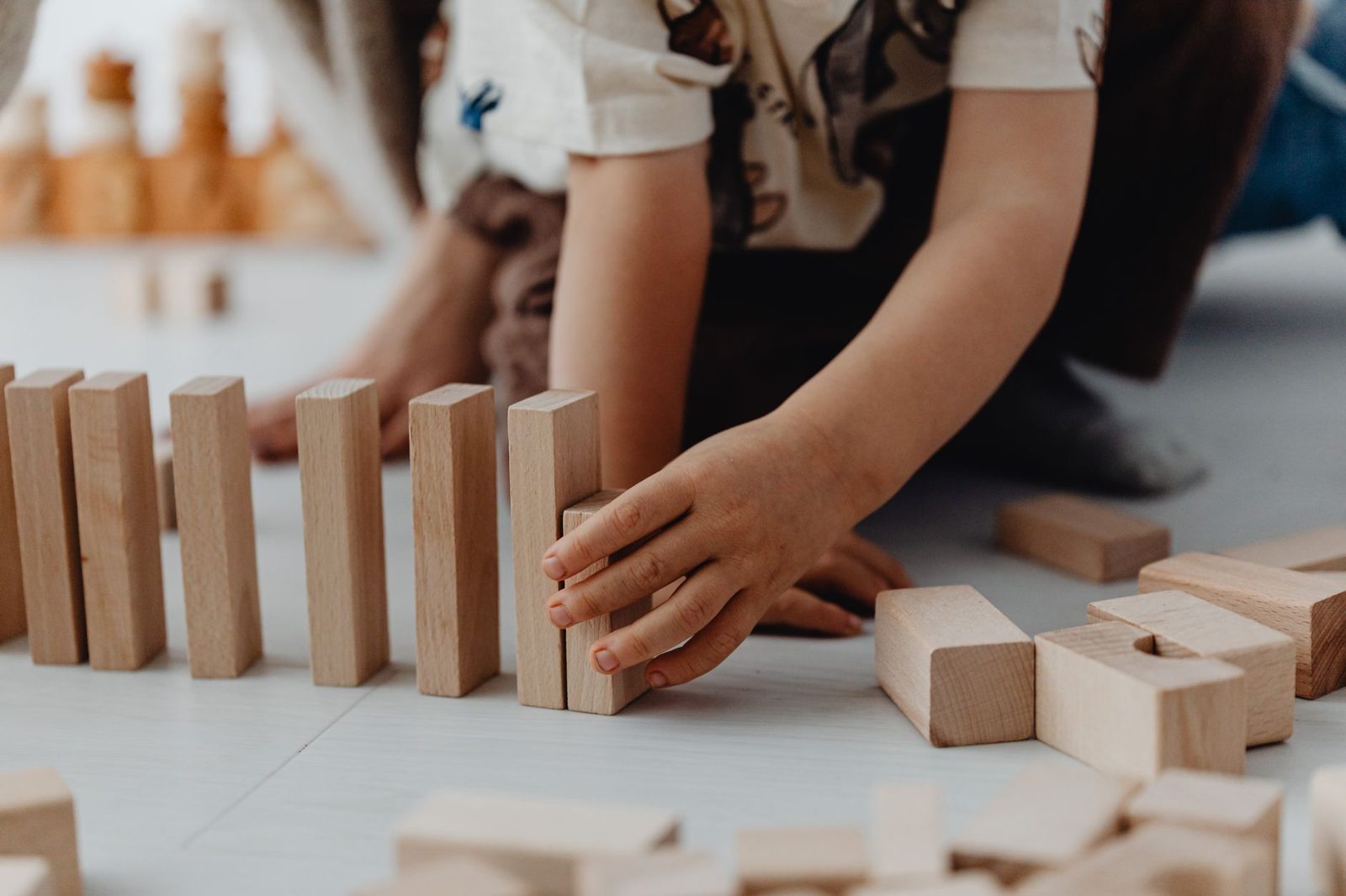 Manos de niños construyendo con bloques de madera natural