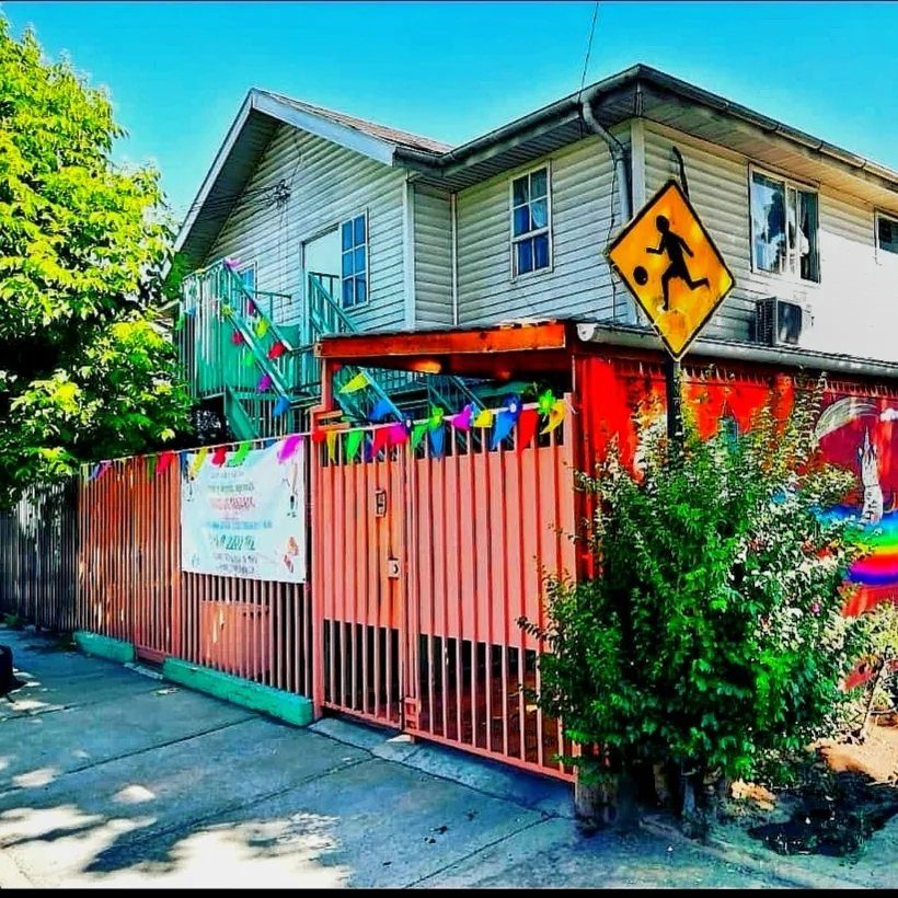 Fachada del jardín infantil Péumafe Montessori en Maipú, con reja naranja y guirnaldas de colores